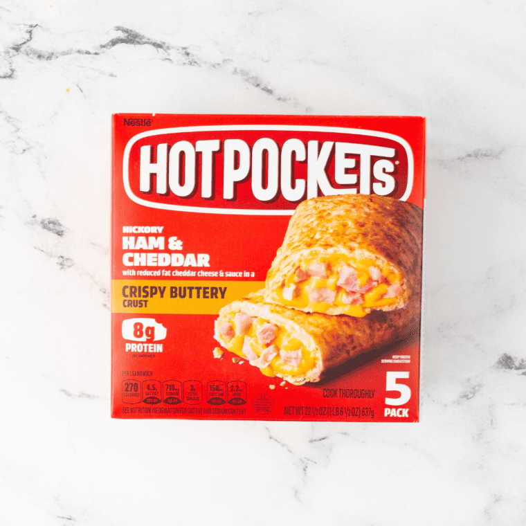 overhead: a box of ham and cheddar flavored hot pockets on a white marble counter