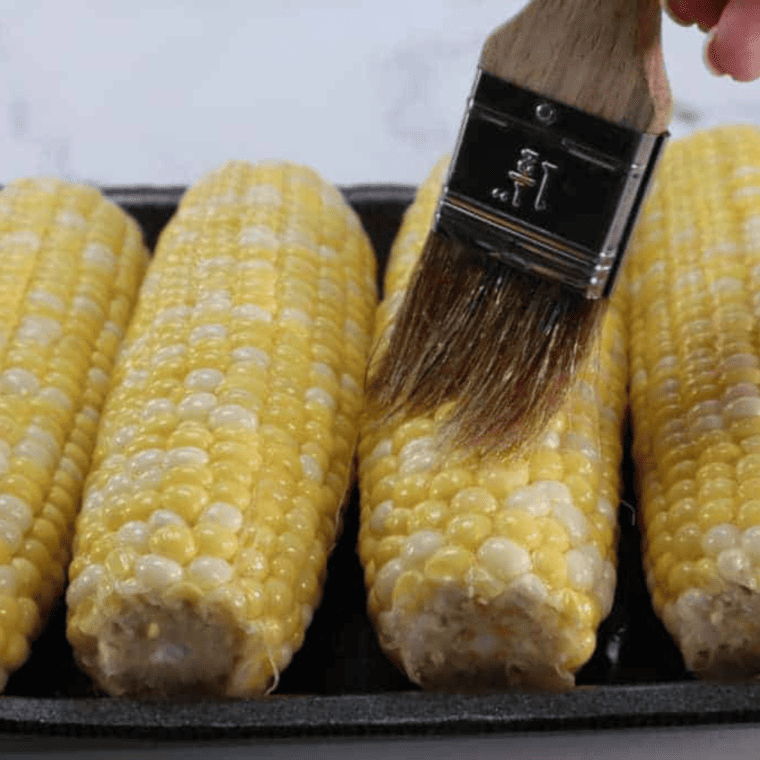 closeup: a brush brushing corn on the cob