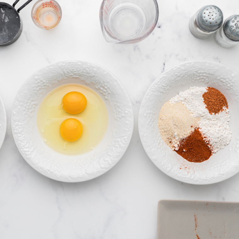 Ingredients laid out on a countertop, including chicken tenders, breadcrumbs, and honey mustard sauce.