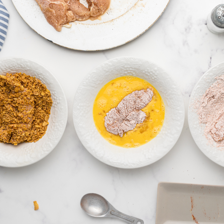 Chicken tenders being coated in breadcrumbs for a crispy texture.