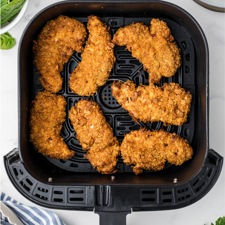 A serving suggestion featuring chicken tenders arranged with dipping sauce and fresh veggies on the side.