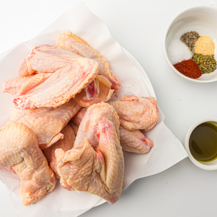 Seasoned Steakhouse Wings Ingredients on plate with herbs on the side.