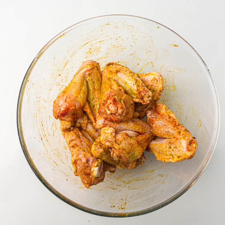 Bowl of uncooked chicken wings coated in olive oil and steakhouse seasonings