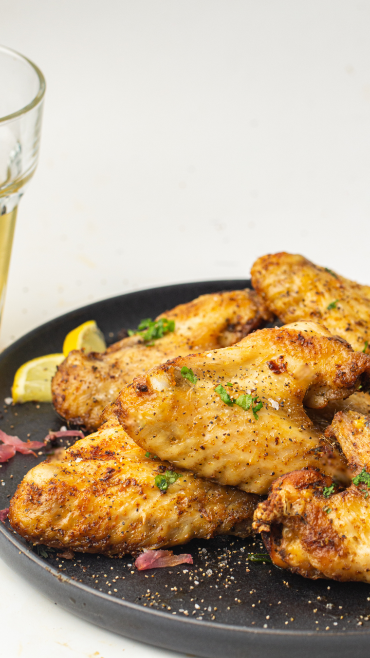 Cooked Seasoned Steakhouse Wings on a plate with fresh herbs on top