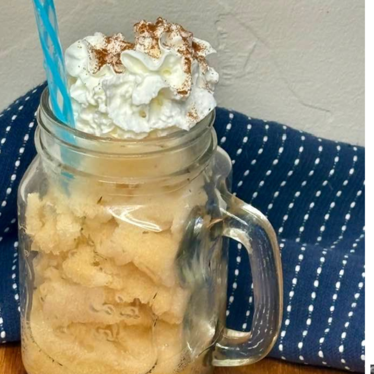 Apple Sider Slushi in a mason jar with a straw, whipped cream and a sprinkle of ground cinnamon.