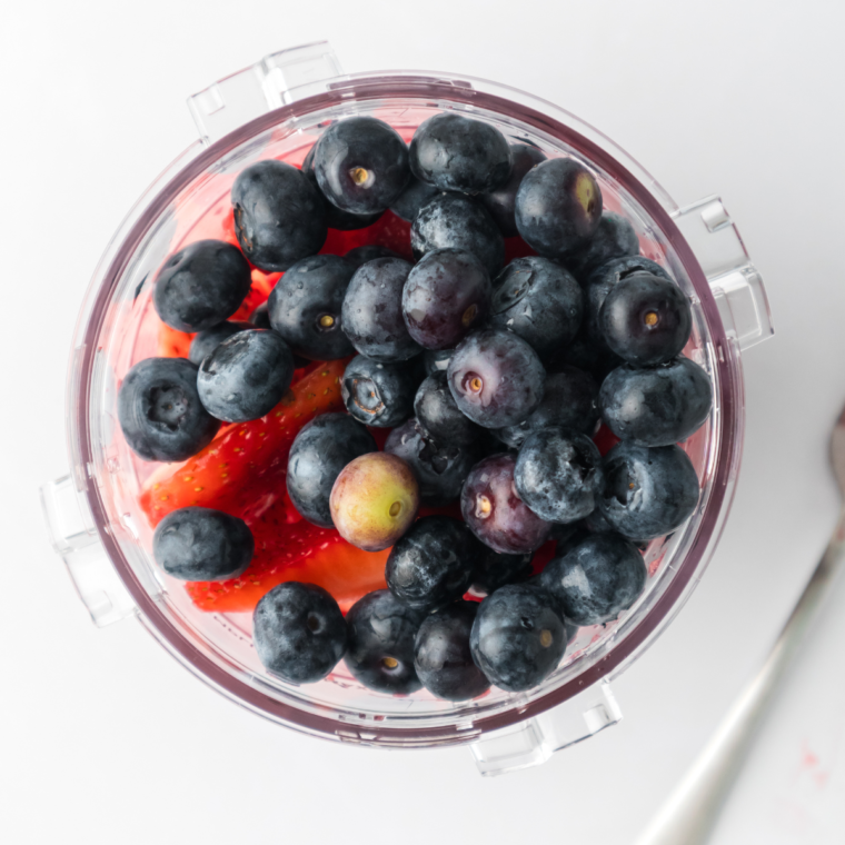 Adding mixed berries to the Ninja Creami empty pint container for making sorbet."