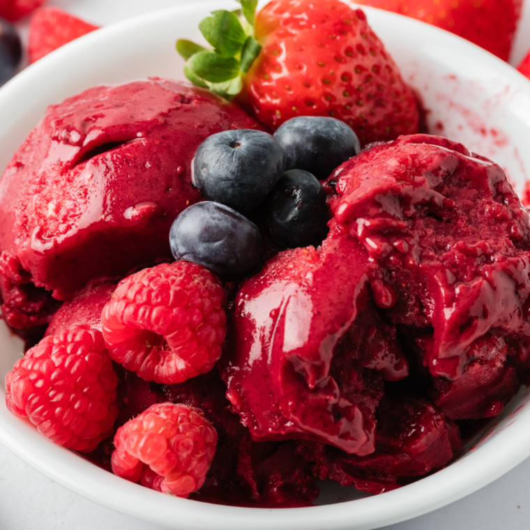 Ninja Creami Mixed Berry Sorbet in a white bowl with fresh berries and mint leaves on top.