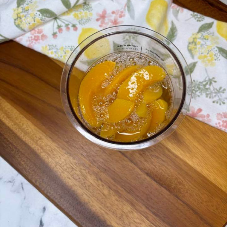 "Pouring the peach mixture into the Ninja Creami pint container."