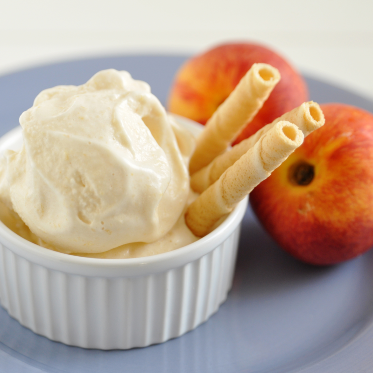 Ninja Creami Peach Sorbet in a bowl, with fresh peaches next to it.