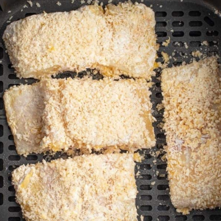 Frozen Cod in air fryer basket, with sesaonings.