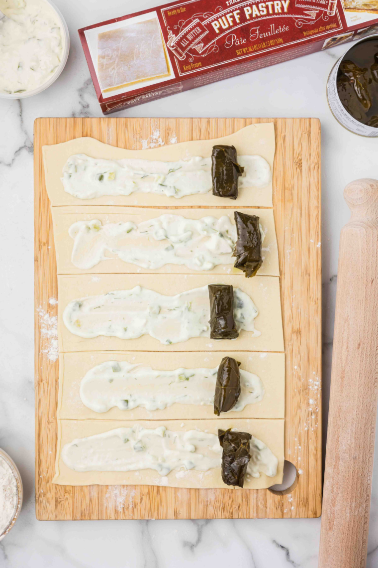 Close-up of grape leaves being rolled with puff pastry for Air Fryer Stuffed Grape Leaves.