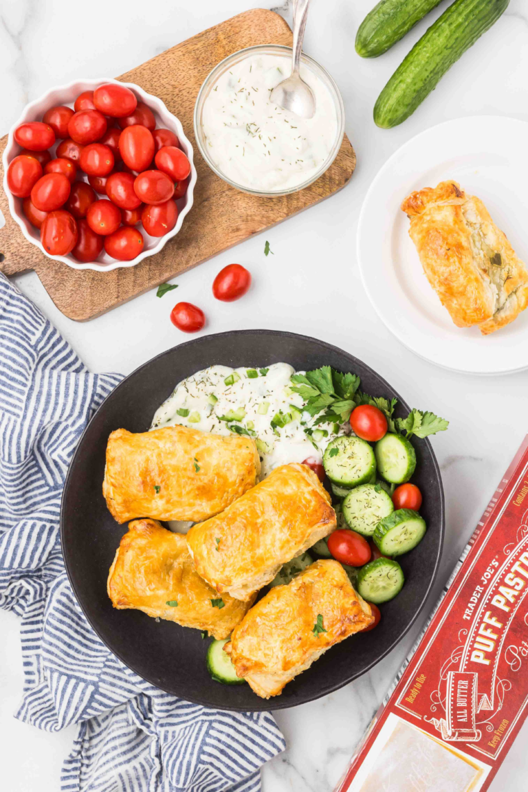 A plate of golden-brown Air Fryer Stuffed Grape Leaves (Dolmas) garnished with fresh herbs and served with a side of tzatziki sauce