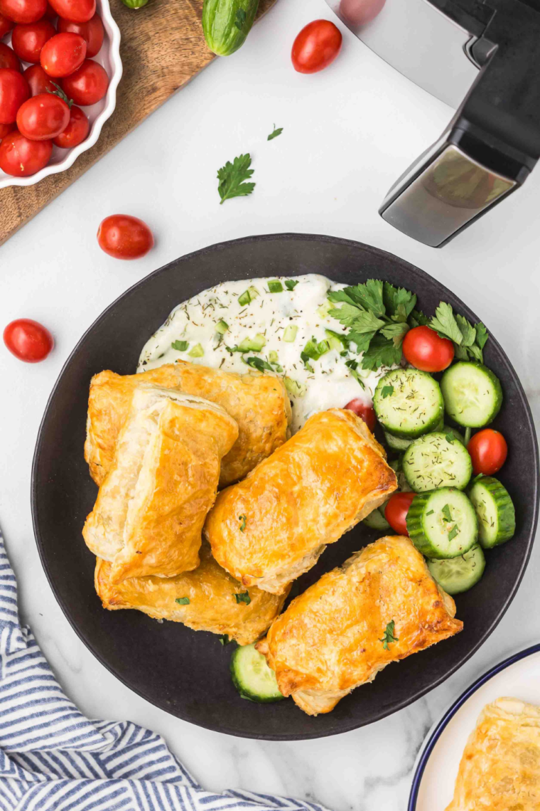 Plate of dolmas wrapped in golden puff pastry on a plate.