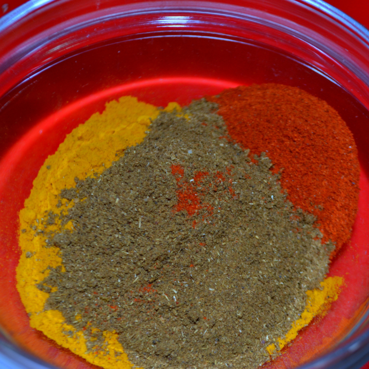 Bowl of Chermoula seasoning blend on a wooden table with fresh herbs