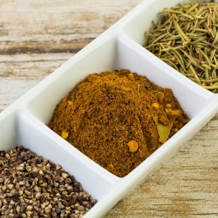 Chermoula spice blend in a small bowl with fresh herbs and spices surrounding it