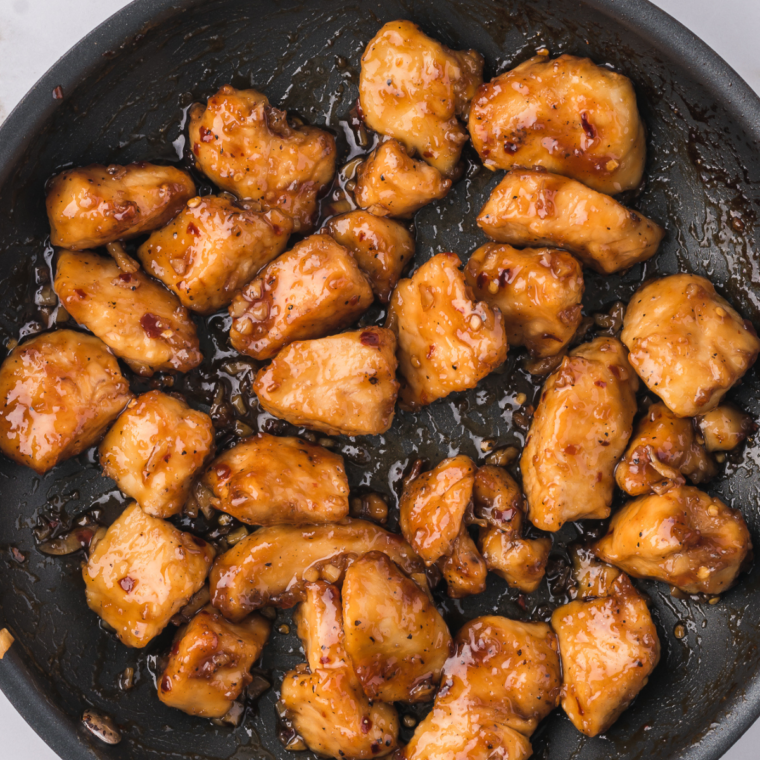 Coating the cooking chicken nuggets with sauce.