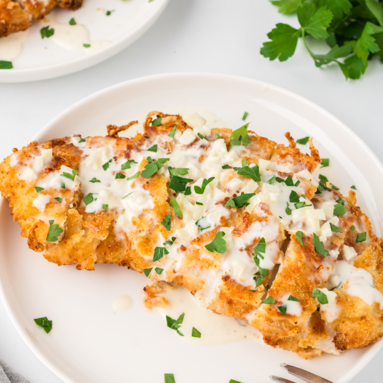 A plate of golden, crispy homemade Crispy Chicken Fritta, an Olive Garden copycat recipe, served alongside pasta and rich sauce.