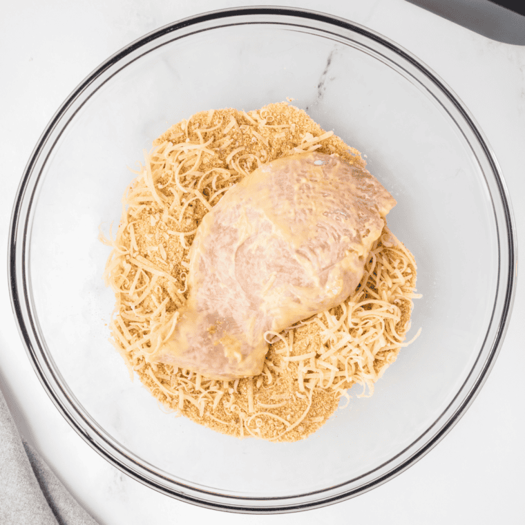 Coating the chicken with the breadcrumbs, parmesan, and seasonings.