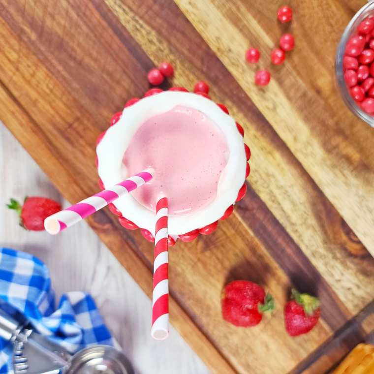 Top view of strawberry milk in a glass with 2 straws