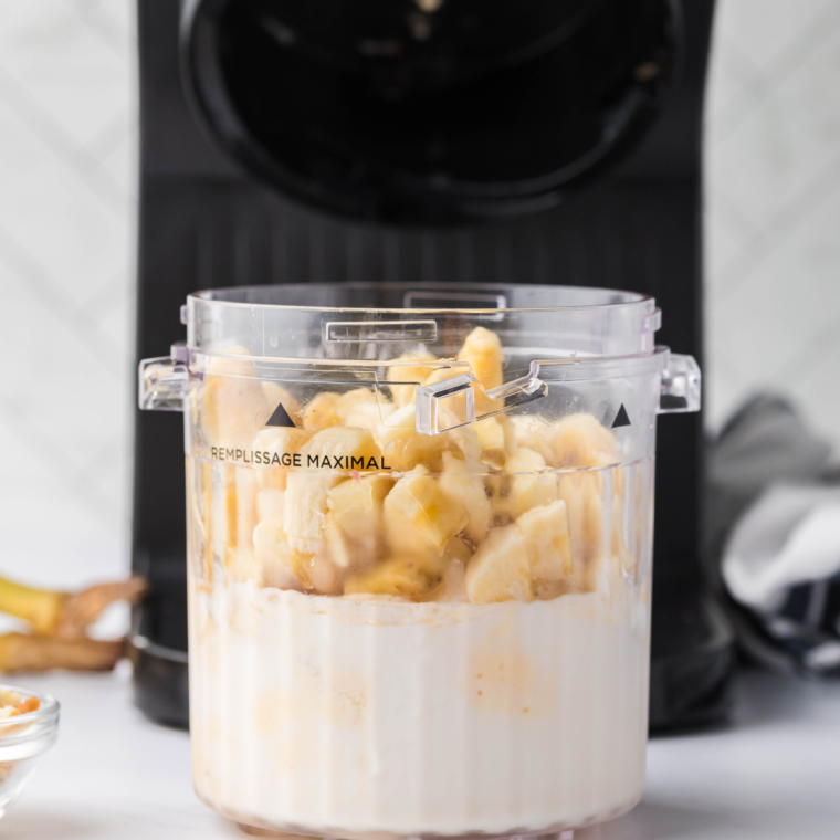 Two ripe bananas being peeled and placed in a mixing bowl for blending.