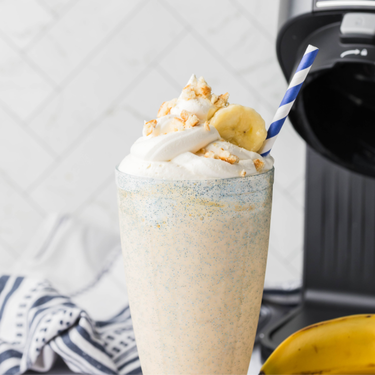 
A refreshing Sonic Banana Shake made with ripe bananas, vanilla ice cream, and topped with whipped cream and banana slices, served in a tall glass with a colorful straw.