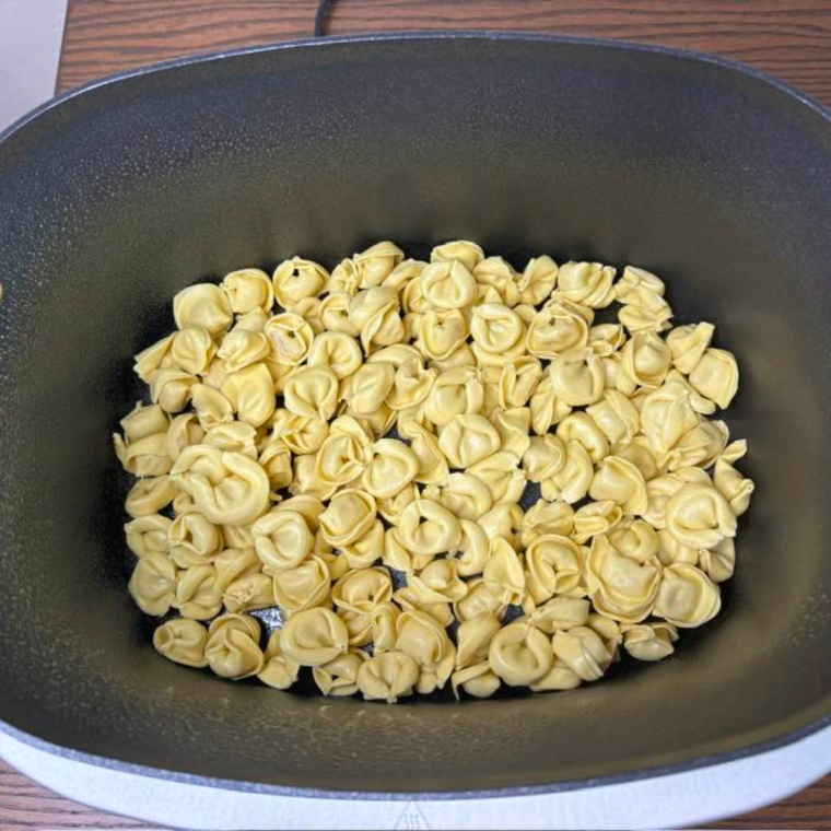 Place tortellini in the Ninja Foodi Possible crockpot, in a single layer.