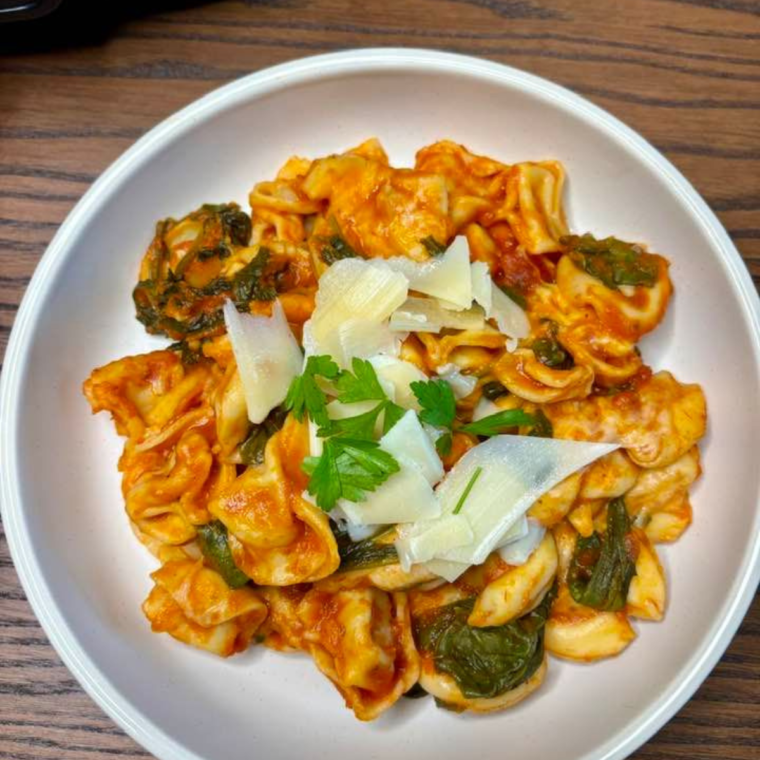 Plate of pasta with cheese, and fresh herbs.