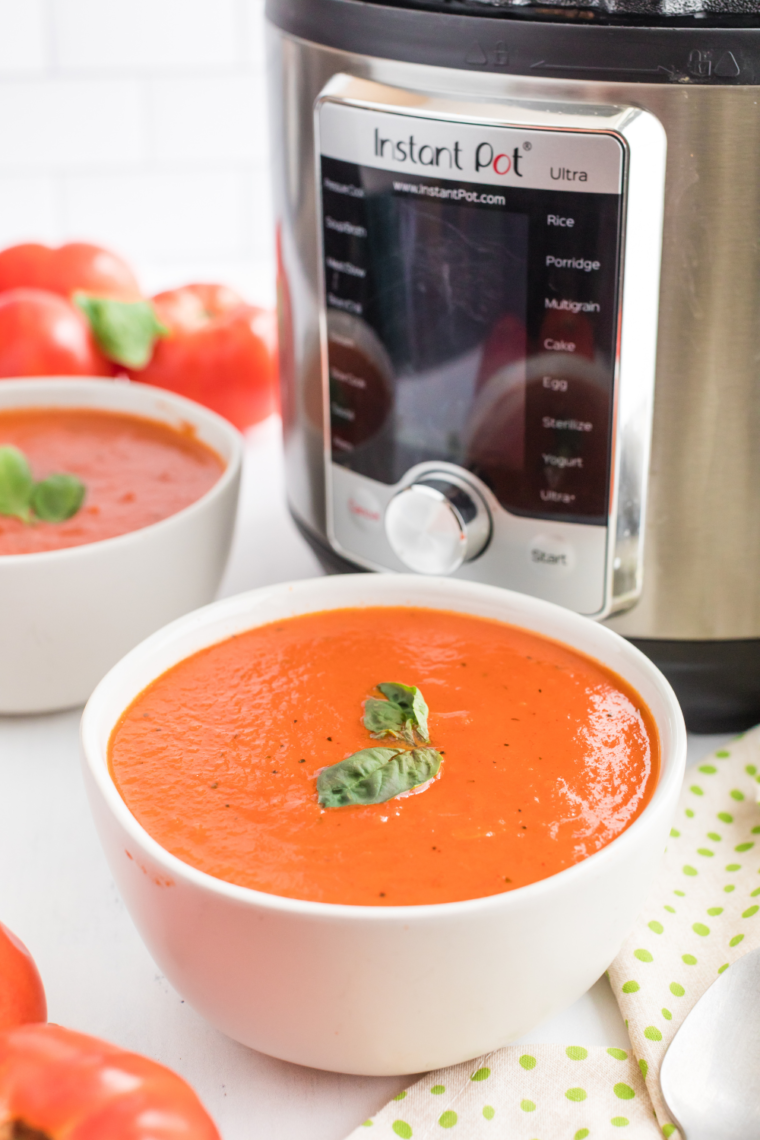 Close-up of creamy tomato soup made in the Instant Pot with basil leaves.