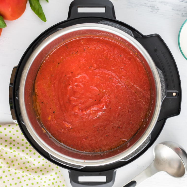 Adding crushed tomatoes to the Instant Pot to create the soup base.