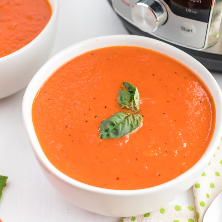 Bowl of Instant Pot Olive Garden Cream of Tomato and Basil Soup garnished with fresh basil.