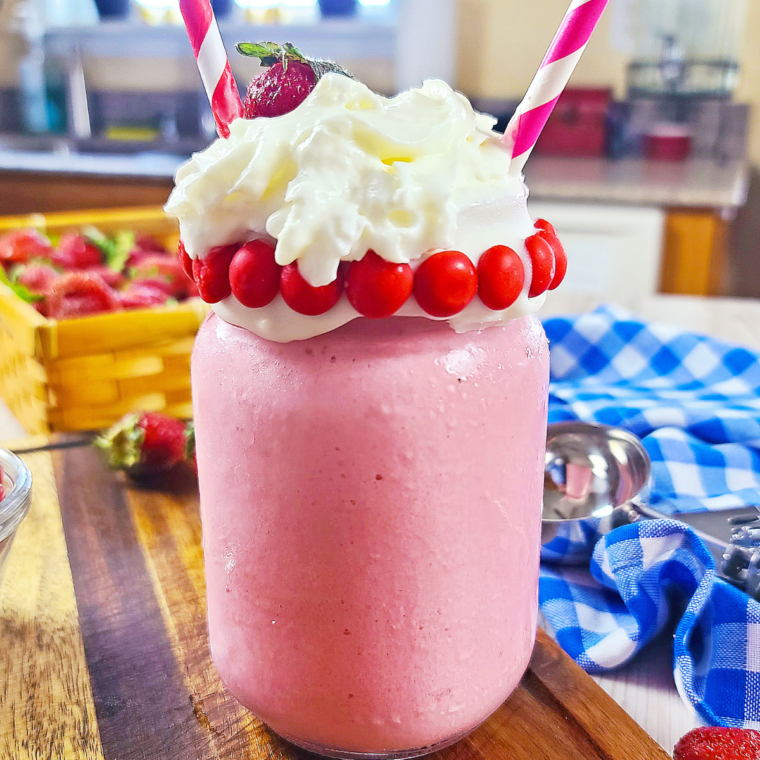 Close-up of a thick and creamy Copycat Wendy's Strawberry Frosty topped with whipped cream.