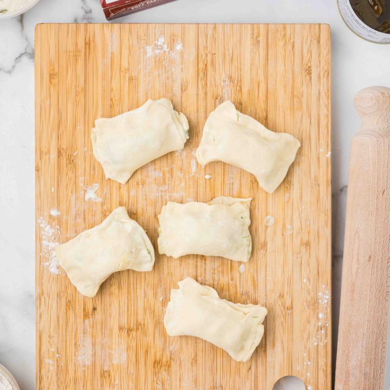 Stuffed grape leaves with wrapped with puff pastry on a cutting board.