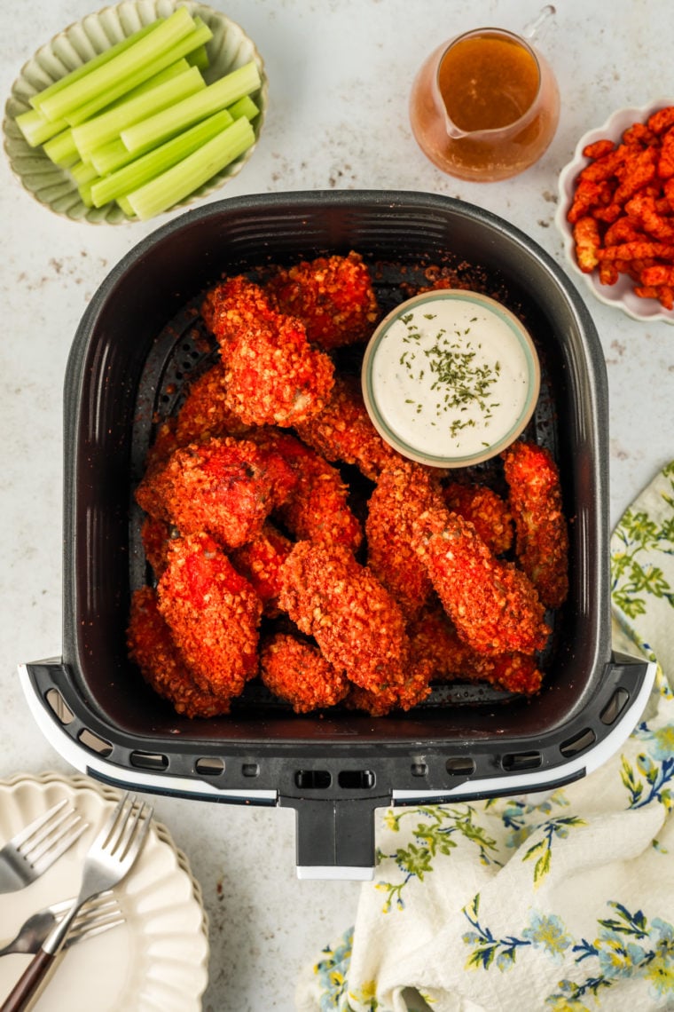 A plate of Air Fryer Flamin' Hot Cheetos Chicken Wings, crispy and vibrant red, garnished with fresh parsley and served with a side of ranch dipping sauce.