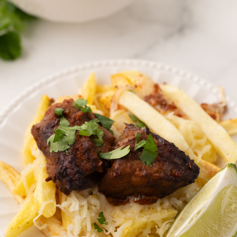 Crispy Air Fryer Birria Fries topped with juicy beef, melted cheese, and a drizzle of consommé.