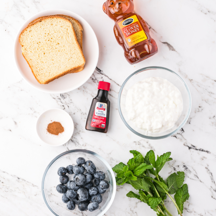 Ingredients needed for blueberry cottage toast on marble kitchen table.