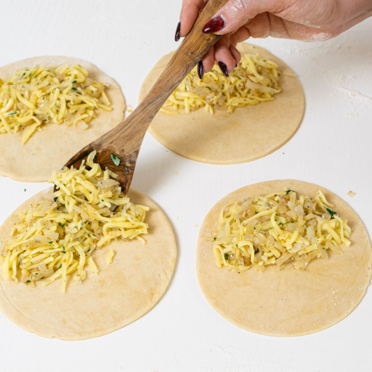 Adding cheese and onion filling to the center of the pastry for pasty.