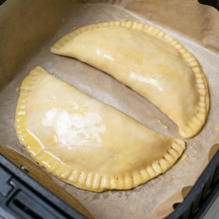 Placing the prepared Air Fryer Cheese and Onion Pasty in the air fryer basket.