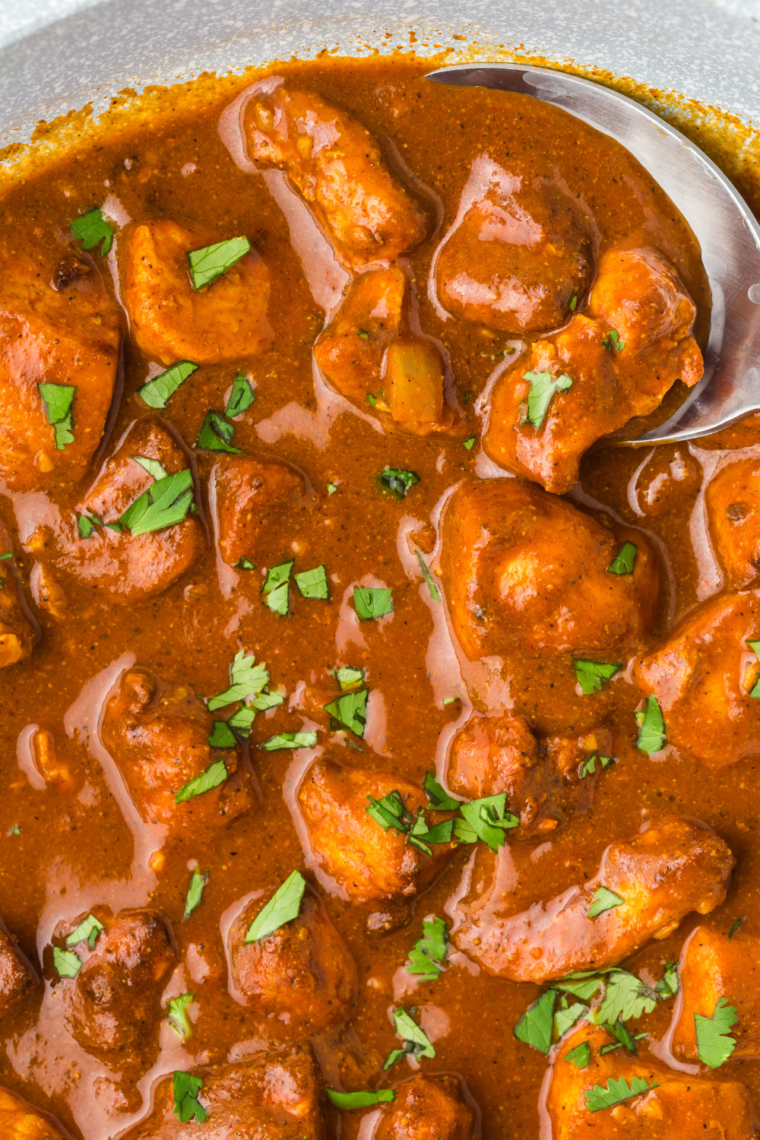 "Air Fryer Chicken Vindaloo with marinated chicken cooked to golden perfection, garnished with fresh cilantro, and served with rice and naan."