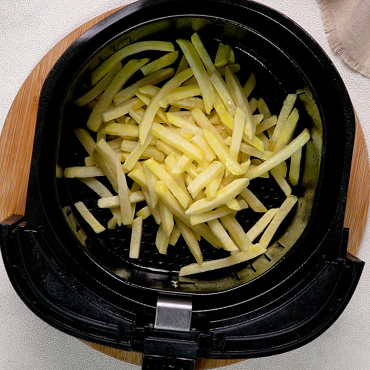 "Golden and crispy French fries arranged in an air fryer basket, cooked to perfection at 400°F, ready for a delicious topping."