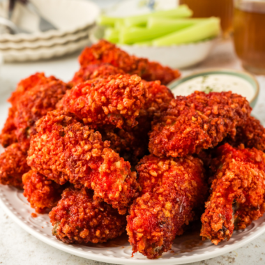 "Air Fryer Flamin' Hot Cheetos Chicken Wings served on a platter with dipping sauce, showcasing their crispy, fiery red coating."