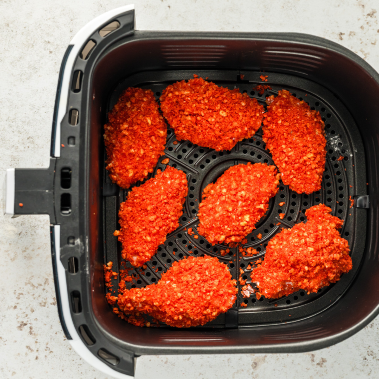 Coated chicken wings in the air fryer basket.