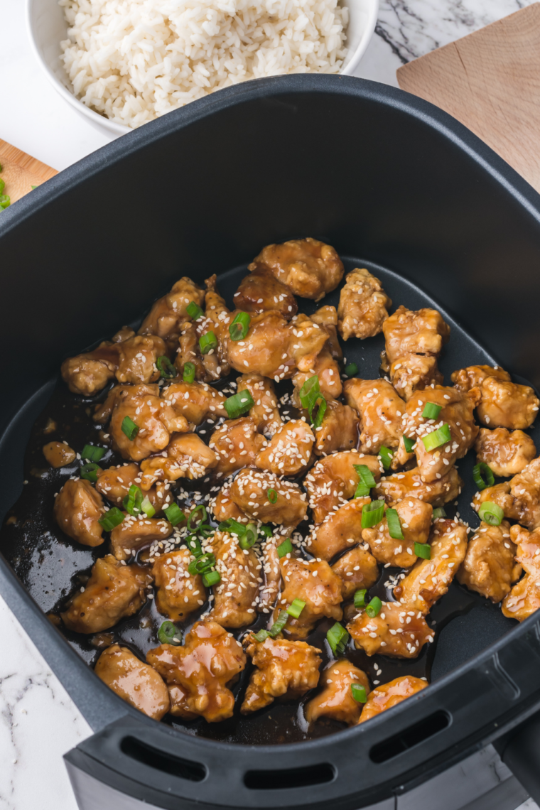 Close-up of PF Chang’s Spicy Chicken Copycat in a white bowl, garnished with sesame seeds.