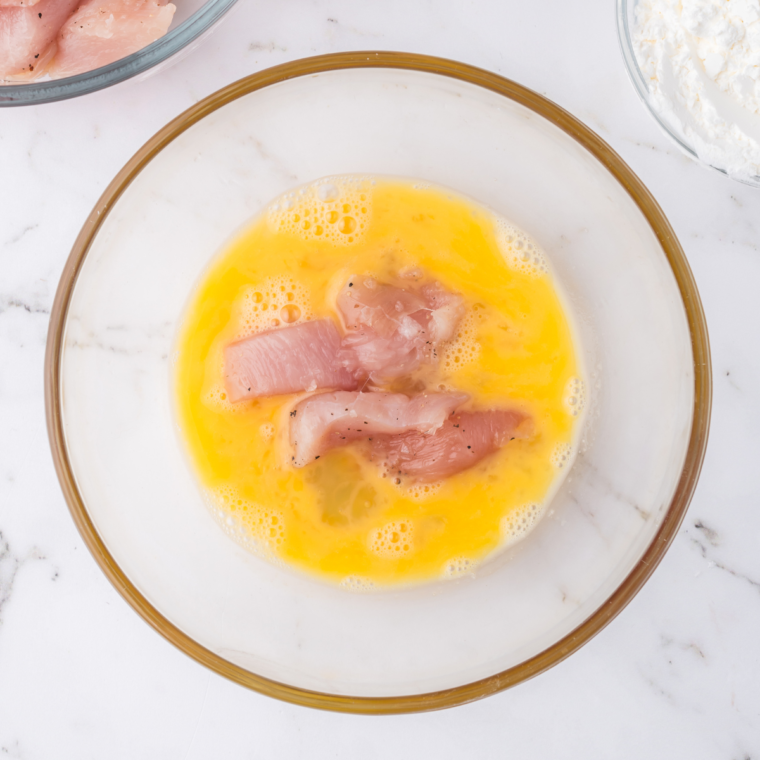 Dip the chicken pieces into the egg wash, making the crispy coating.