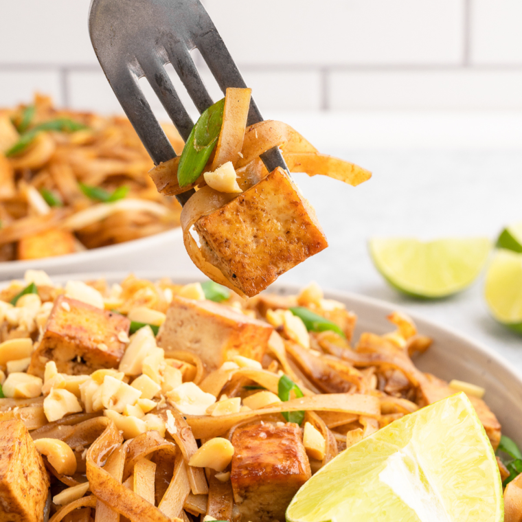 Air Fryer Pad Thai garnished with lime, peanuts, and fresh herbs.