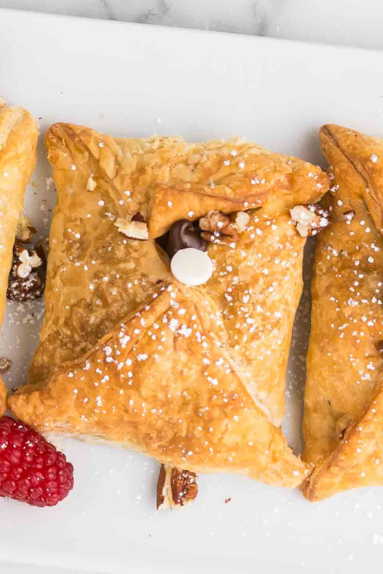 "Golden Air Fryer Raspberry Chocolate Puffs filled with rich chocolate and sweet raspberries, dusted with powdered sugar, and served on a white plate."