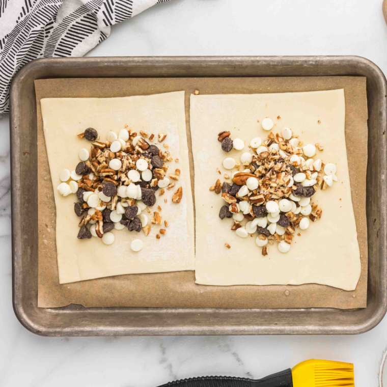 "Rolled puff pastry sheets on a floured surface, cut into four equal 6-inch squares."