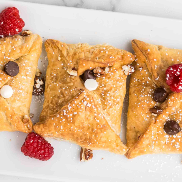 "Golden Air Fryer Raspberry Chocolate Puffs filled with chocolate and raspberries, served on a plate and dusted with powdered sugar."