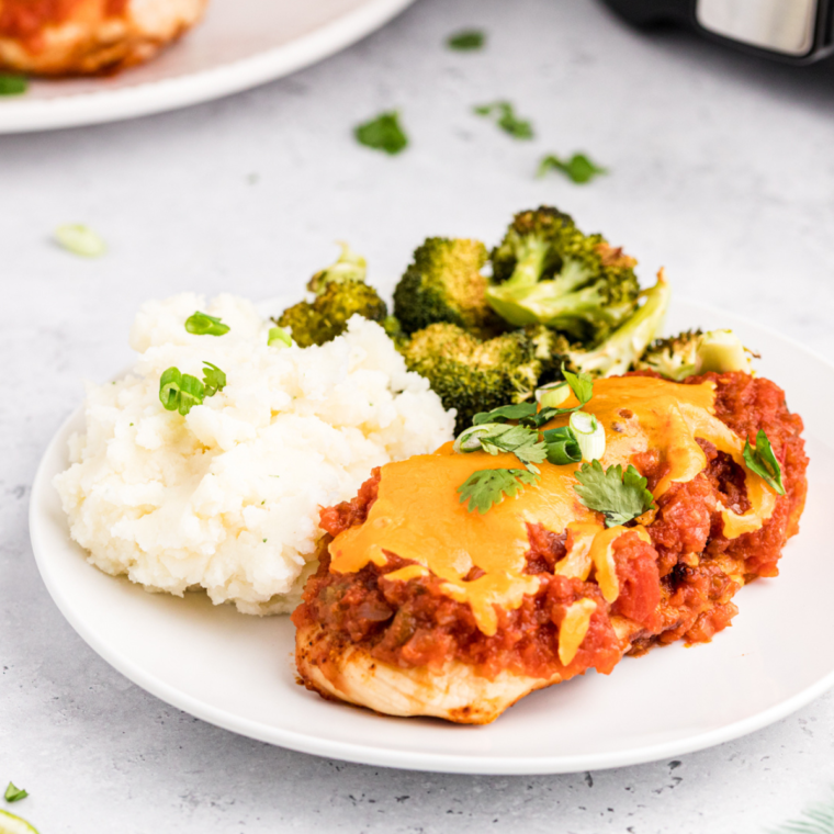 "Air Fryer Salsa Chicken topped with fresh cilantro and served with lime wedges on a plate."