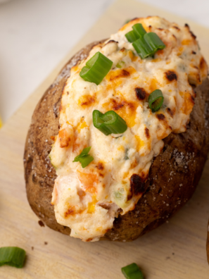 A loaded Air Fryer Seafood Baked Potato topped with creamy seafood filling, garnished with fresh herbs, served on a white plate.
