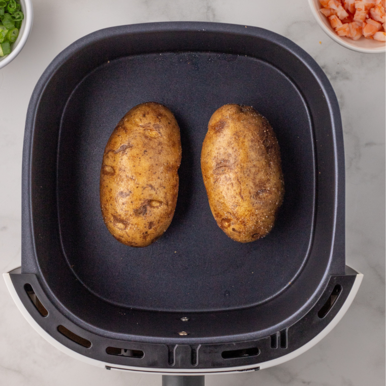 "Air fryer preheated to 400°F (200°C) with potatoes pricked, rubbed in olive oil, seasoned with salt and pepper, and placed in the basket, cooking to tender perfection."